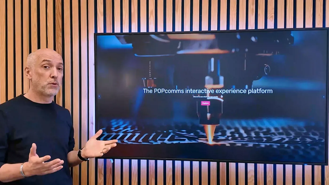 Presenter standing beside a large interactive display showing a product experience